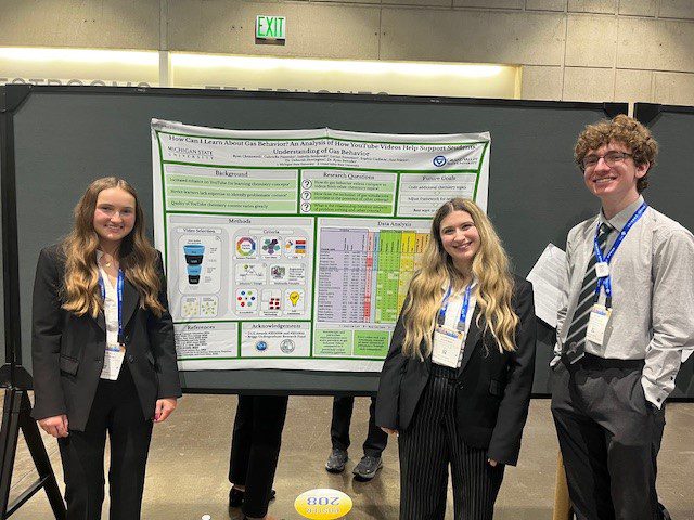 Three students in front of a scientific poster